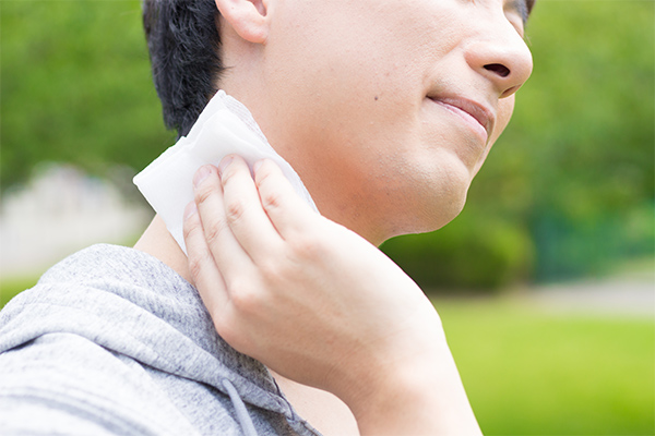 屋外で汗を拭っている男性