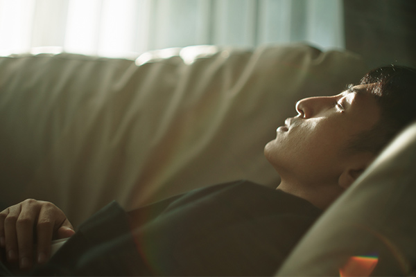ベッドで睡眠を取る男性