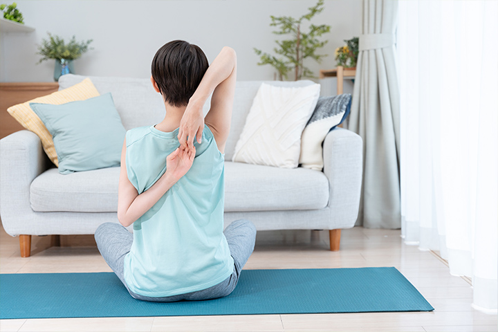 ストレッチで肩を引き伸ばす女性