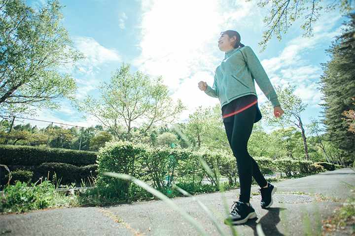 青空の下でウォーキングをする女性